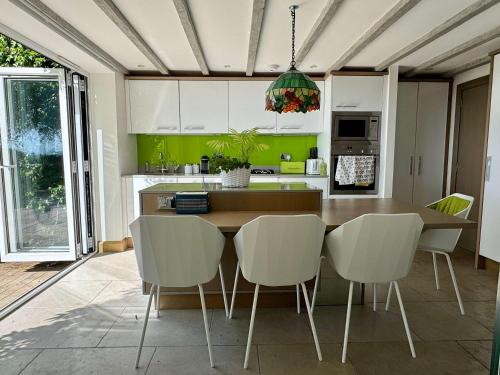 a kitchen with a wooden table and white chairs at 2-Bed Cottage Garden Views near the Peak District in Macclesfield