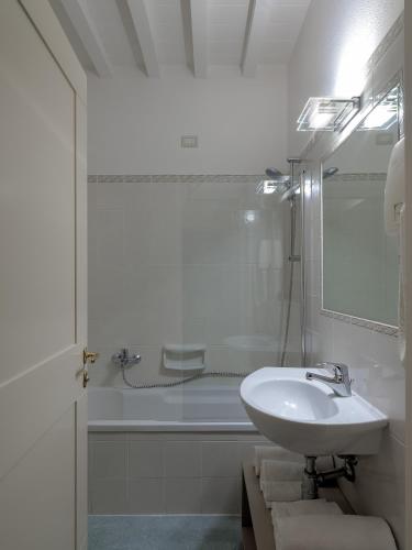 a white bathroom with a sink and a bath tub at Resort Casale Le Torri in Ponsacco