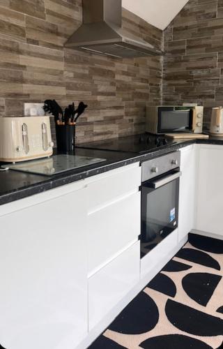 a kitchen with white cabinets and a stove top oven at Beautiful holiday home South Beach Blyth 3 minute walk to the beach in Newsham