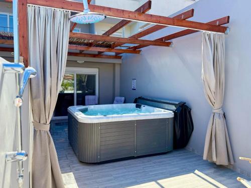 a large hot tub in a patio with curtains at Peter's Place Studios & Suites in Faliraki