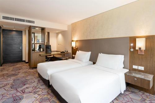 a hotel room with two beds and a desk at Radisson Suites Bangkok Sukhumvit in Bangkok