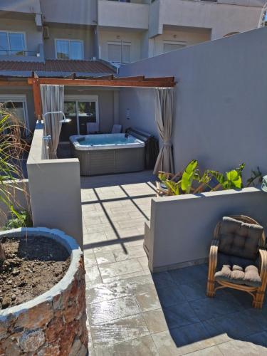 a patio with a hot tub and a chair at Peter's Place Studios & Suites in Faliraki