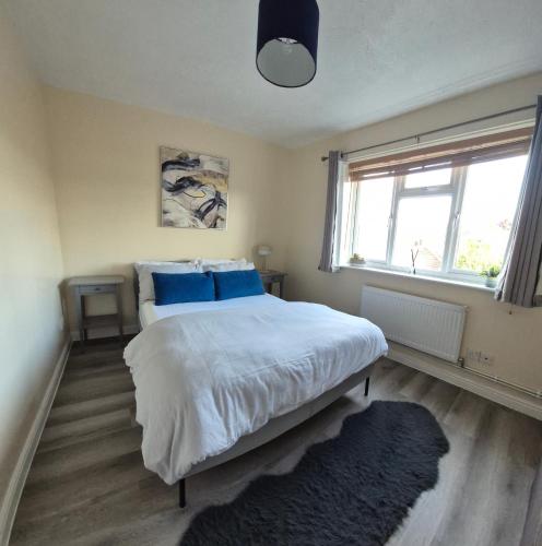 a bedroom with a bed with blue pillows and a window at Cosy 2 Bedroom House Stevenage Old town Close to Train Station Free Parking Sleeps 4-6 in Stevenage