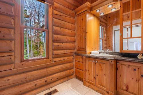 a log cabin bathroom with a sink and a window at Le Cerf 53 Fiddler Lake in Mille-Isles