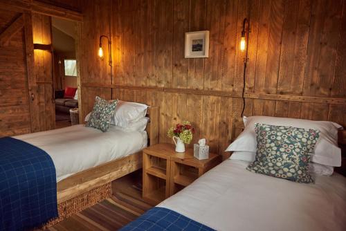 two beds in a room with wooden walls at Pippin Lodge in Glastonbury