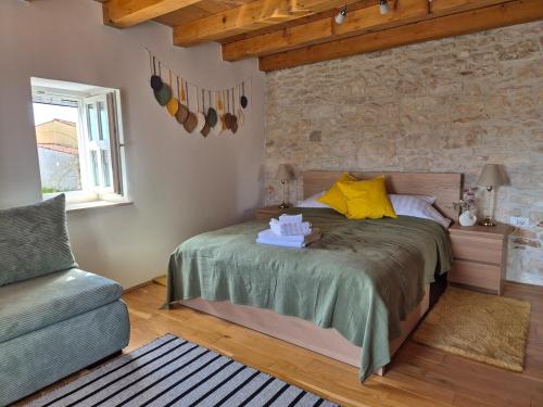 a bedroom with a bed and a chair at Akvamarin Stone House Istria in Medulin
