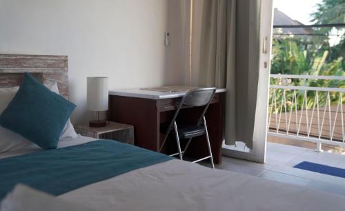 ein Schlafzimmer mit einem Bett und einem Schreibtisch mit einem Fenster in der Unterkunft The shortcut rooms in Canggu