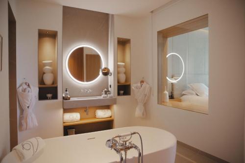 a bathroom with a white tub and a mirror at Domaine de Verchant & Spa - Relais & Châteaux in Montpellier