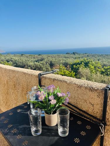 a table with flowers and glasses on a balcony at Mani Spot Nezoulas in Álika