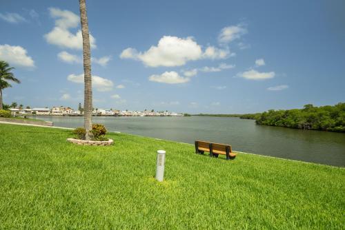 a park bench sitting in the grass next to a river at Nettles Island 1383 in Jensen Beach