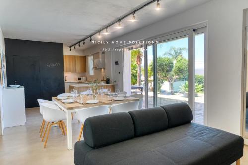 a kitchen and dining room with a table and a couch at Oasi Elegante Piscina di Lusso - vista panoramica By Sicily Home Solutions in Alcamo