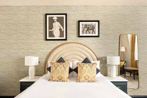a bedroom with a white bed with three pictures on the wall at Hotel Indigo London - Kensington by IHG in London