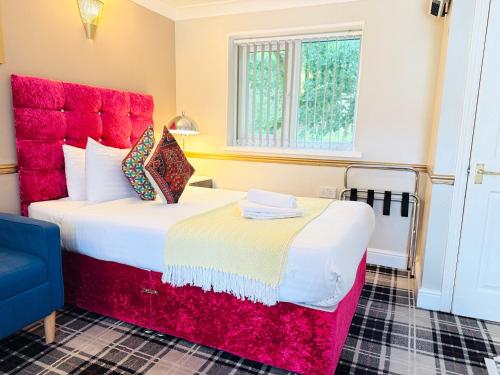 a bedroom with a large bed with a red headboard at 4 Sisters Inn in Theydon Bois
