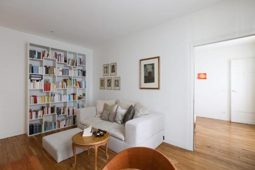 - un salon avec un canapé blanc et une étagère à livres dans l'établissement Bright apartment for 4 with balcony, à Paris
