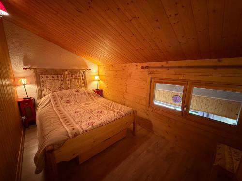 une chambre avec un lit dans une cabane en bois dans l'établissement Appartement cosy 2 pièces + mezzanine, balcon, animaux tolérés - FR-1-293-116, aux Saisies