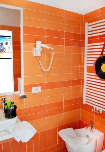 an orange tiled bathroom with a sink and a mirror at B&B Seventy Design in Dimaro
