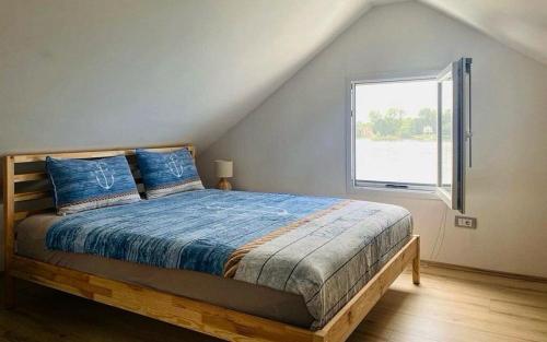 a bedroom with a bed with a large window at Splav Casa Luna in Ostružnica