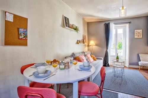 - un salon avec une table blanche et des chaises rouges dans l'établissement Embruns - F2 400m de la mer - Juno Beach, à Bernières-sur-Mer