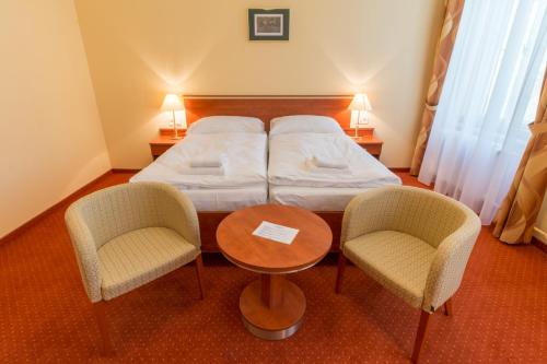 a bedroom with a bed and two chairs and a table at Ensana Svoboda in Mariánské Lázně