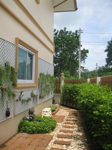 a garden with a brick walkway next to a house at 2N Guesthouse in Phetchaburi