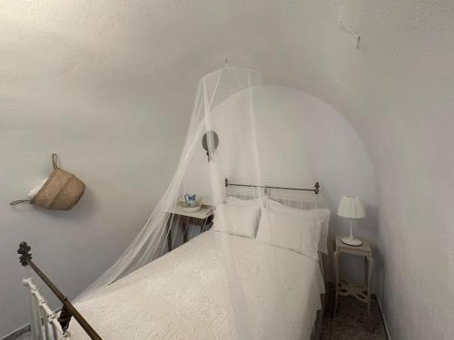 a white bedroom with a canopy bed with white pillows at Panoramic view apartment in Megalokhori