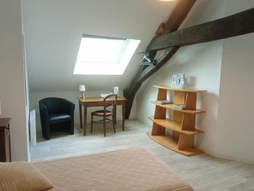 une chambre mansardée avec un bureau et une table avec une fenêtre dans l'établissement Les Charmilles, à Saint-Jean-de-Losne