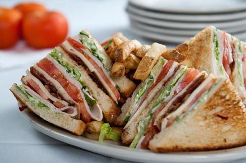 a sandwich cut in half on a plate with fries at Hotel Niagara in Lido di Jesolo