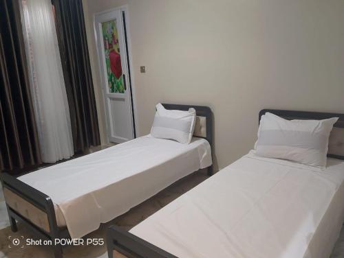two beds in a room with white sheets and pillows at Dortoir 25 Constantine in Constantine