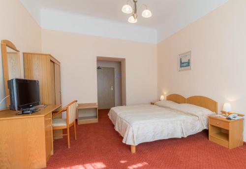 a bedroom with a bed and a desk with a television at Ensana Svoboda in Mariánské Lázně