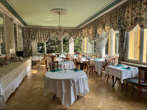 a restaurant with white tables and chairs and windows at Hotel Restaurant Du Parc in Thann
