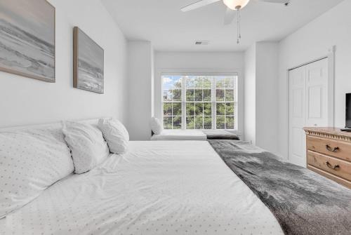 a white bedroom with a large bed and a window at Myrtlewood by Monarch Rentals in Myrtle Beach