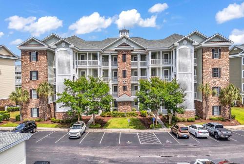 a large building with cars parked in a parking lot at Myrtlewood by Monarch Rentals in Myrtle Beach