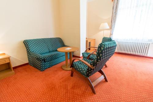 a room with a couch and a chair and a table at Ensana Svoboda in Mariánské Lázně