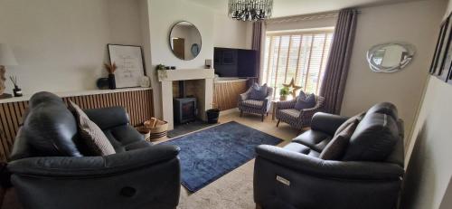 a living room with two chairs and a fireplace at Coastal Rest in Beadnell