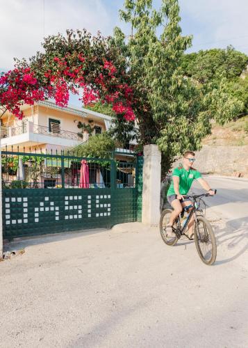 a man riding a bike in front of a house at Oasis Hostel in Himare