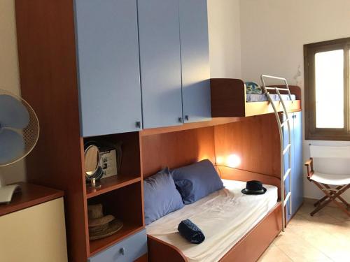 a small bedroom with a bunk bed with blue pillows at AffittaSardegna - Casa delle Dune in Capo Comino