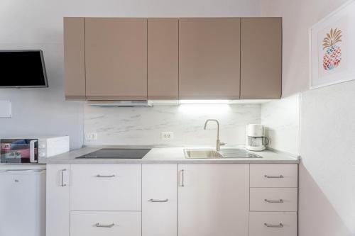 a white kitchen with white cabinets and a sink at Casa Rosi in Frontera