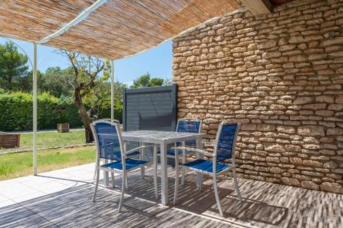 une table et des chaises sur une terrasse avec un mur en pierre dans l'établissement Small T2 cottage in provencal style, à La Roque-sur-Pernes