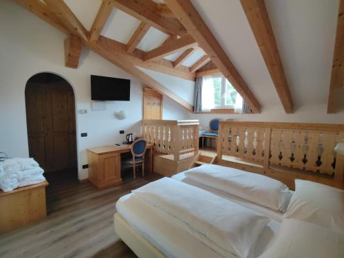 a bedroom with two beds and a desk and a tv at Hotel Valacia in Pozza di Fassa