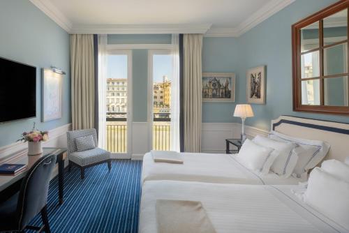 a hotel room with a bed and a desk and a window at Hotel Lungarno - Lungarno Collection in Florence