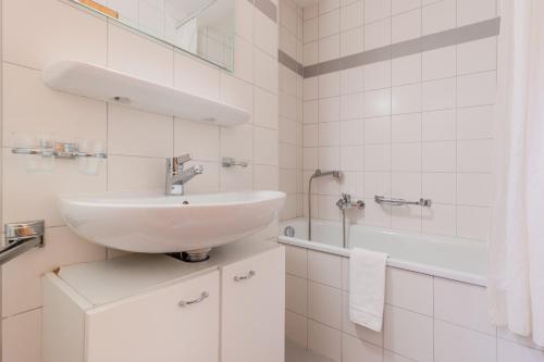 a white bathroom with a sink and a tub at Pracondu 1 304 - OUTDOOR & FUN charming apartment in Nendaz