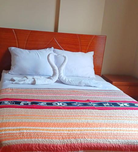 a bed with two swans made out of pillows at Haylli Café Oro Hotel in Santa Teresa