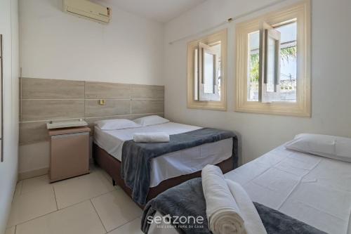a bedroom with two beds and two windows at Casa c/ piscina e churrasq. Porto S. - BA FLO001 in Coroa Vermelha