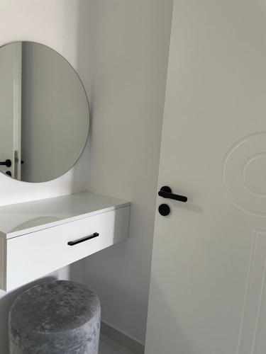 a bathroom with a sink and a mirror and a stool at Vila Ori in Ksamil