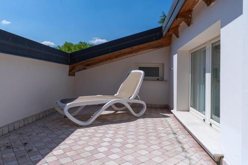 a white chair sitting on the porch of a house at Monastero Resort & Spa - Garda Lake Collection in Soiano del Lago