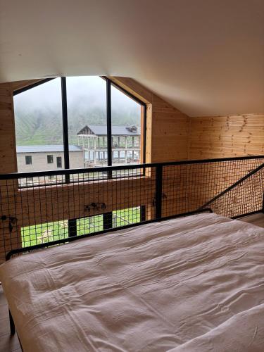 a large bed in a room with a large window at Mountain View in Stepantsminda