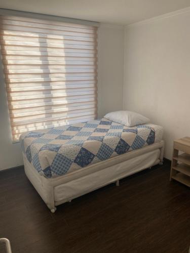 a bedroom with a bed with a blue and white blanket at Mar Egeo departamento in Iquique