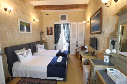 a hotel room with two beds and a television at The Knight - Experiential Heritage Home at Birgu Square in Birgu