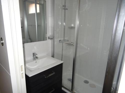 une salle de bain blanche avec une douche et un lavabo dans l'établissement Résidence Le Bali, à La Ciotat