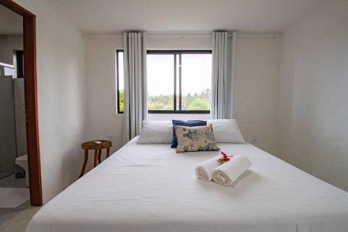 ein Schlafzimmer mit einem großen weißen Bett mit Handtüchern darauf in der Unterkunft Casa Em Milagres 03 suítes - 300m da Praia in Tatuamunha